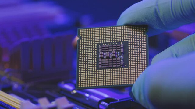 Concept of computer, motherboard, hardware and technology. Laboratory technician holds a powerful processor in his hands. CPU computer processor shallow focus. CPU socket of the computer's motherboard