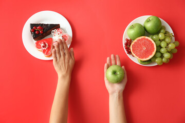 Top view of woman choosing between sweets and healthy fruits on red background, closeup