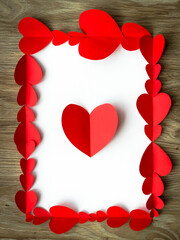 Valentine's Day background. Red paper hearts are lined with rectangle, on a wooden background with place for text with hearts. Bright colorful hearts for postcards. - 404883494