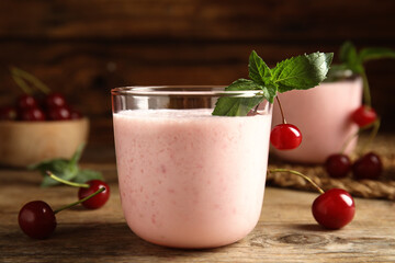 Tasty fresh milk shake with cherries on wooden table, closeup