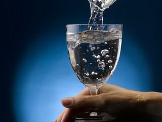Beautiful female hand holds a stem glass of water