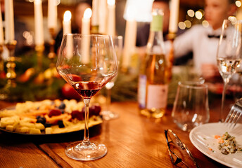 glass of wine on a wooden table during a festive candlelit dinner. romantic date. utensils for alcoholic beverages. Low light. Selective focus.