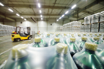 Yellow loader on the background of a huge industrial food warehouse with plastic PET bottles with beer,  water,  drinks.