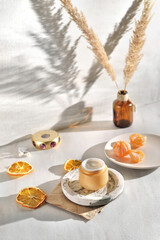 Beauty lifestyle background with Opened Jar of face cream and fresh tangerines.  winter skin care concept