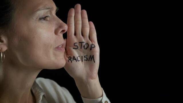 White woman against racism. Caucasian female on a black background shouts stop racism.