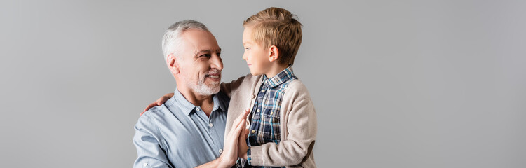 happy man giving high five to grandson while holding him isolated on grey, banner