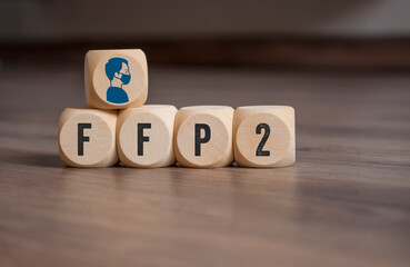 Cubes, dice or blocks with acronym FFP2 filtering face piece and mask icon on wooden background