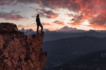 Fototapeta premium Adventurous man is standing on top of the mountain and enjoying the beautiful view. Taken on top of Cheam Peak in Chilliwack, East of Vancouver, BC, Canada. Colorful Sunset Sky Art Render