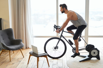 Handsome young man riding stationary exercise bike