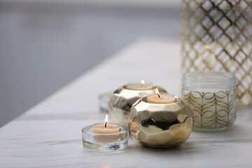 Burning candles in holders on white marble table indoors