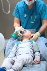 The little boy is placed under anesthesia. Preparation for dental surgery to remove multiple...