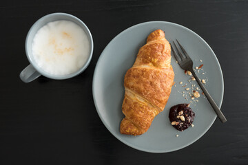 Crispy croissants with jam and smashed walnuts on a plate with fork for a breakfast. Fresh croissant as breakfast. French croissant.