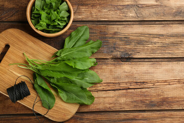 Fresh green sorrel leaves and thread on wooden table, flat lay. Space for text