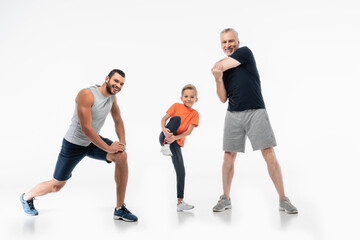 boy with dad and grandpa in sportswear demonstrating power while smiling at camera on white
