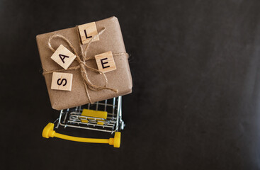 Season of sales in online stores. Cart and sales word on dark blue background. Creative idea for a...