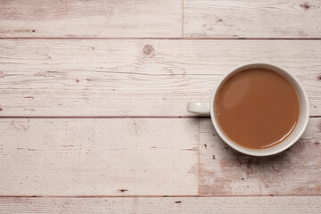 Fototapeta na wymiar Cup of strong tea or coffee with milk in a white mug on a textured white wooden table surface with copy space and room for text