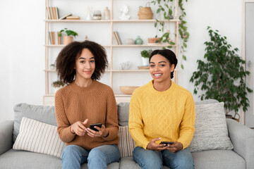 Fototapeta premium Online shopping, offer, advertising and chat. Cheerful attractive millennial african american women with smartphones