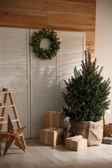 Spacious room with small Christmas tree and wreath. Interior design
