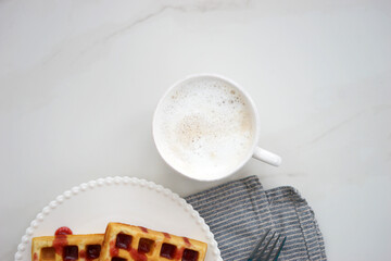 Breakfast with Belgian waffles and coffee and milk foam