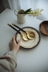 female hand holding beige plate with vintage cutlery on white table