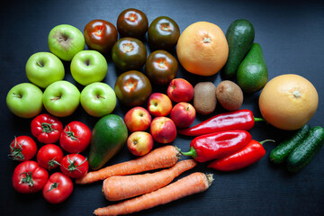 Vegetables and fruits on black background, top view