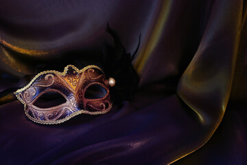 Photo of elegant and delicate gold Venetian mask over dark silk background