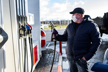 Hand refilling the car with fuel at the refuel station.