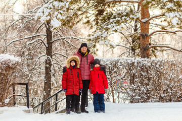 Fototapeta na wymiar Happy father and two sons in red down jackets in winter
