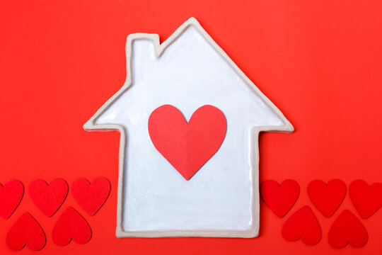 White ceramic plate in the shape of a house with a red heart. Real estate concept, cozy home
