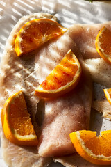 Cod fish fillet with oranges on baking paper. Seafood, healthy eating. Natural light. Top view.