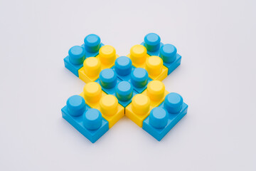 Blue yellow plastic cross figure made of blocks
