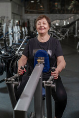 an elderly woman in the gym performs deadlifts in a horizontal block