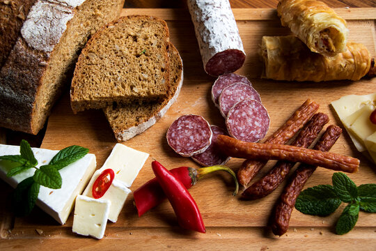 aufschnittplatte mit verschiedenen wurstsorten, brot, k&auml;se, peperoni und gef&uuml;llten bl&auml;tterteigrollen 
