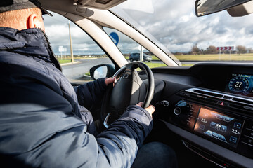 Driving a car. A man sitting behind the wheel of a car and holding the wheel.