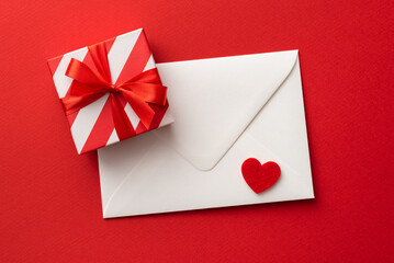 Gift box, heart and envelope on red background