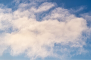 Fluffy white clouds in a deep blue summer sky.