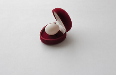 Red velvet box for a wedding ring with an egg inside on a white background. Love concept....