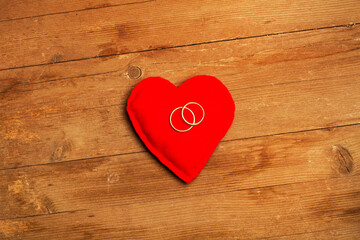 Corazón de fieltro rojo y anillos de boda sobre fondo de madera rústico. Vista superior. Copy space