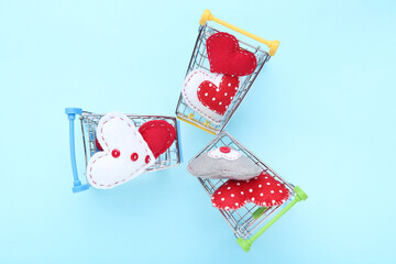 Fabric hearts with shopping carts on blue background