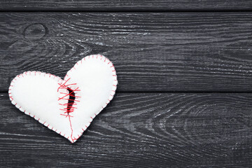 Broken white fabric heart on black wooden table