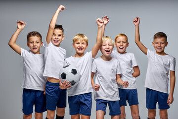 boys soccer team celebrating a victory after match, motivated children sports team rising hands up