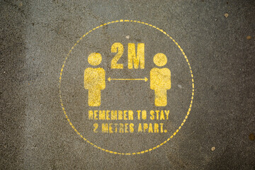  Social Distancing Please keep 2 metres apart yellow sign on pavement