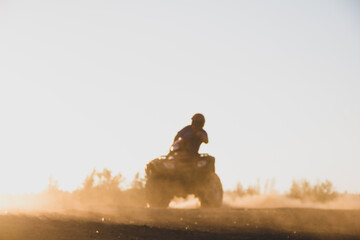 Action shot of child turning on atv quad with dust in sunset. © Piotr