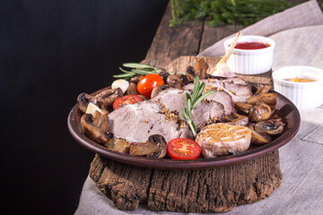 Slices of roasted meat. Cold-boiled pork with mushrooms, potato, garlic and cherry tomato on parchment