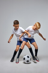 Fototapeta na wymiar children soccer team on training, two boys practicing game with a soccer ball in studio. training football session for children on soccer camp. young boy improving dribbling skills