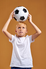 child boy holding soccer ball over head, enjoy sport activities. isolated portrait . football