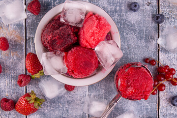Balls of homemade strawberry, red currant, raspberry, blueberry ice cream, sorbet in bowl, scoops,...