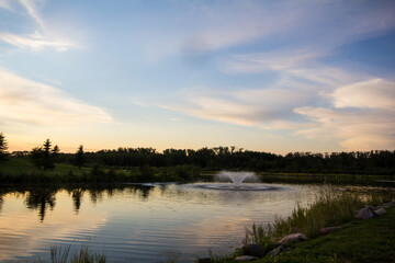 Fototapeta na wymiar Fountain with soft clouds on lake.