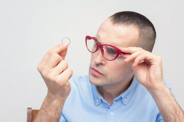 Concentrated man looks at his wedding ring, white background