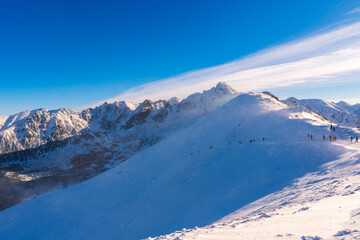 Obraz premium Winter mountain landscape. Sun shines through mountain peak at snowy hills. Winter scene in Tatra mountains, Poland.